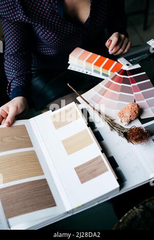 Designer's Hand Choosing Color From Various Color Swatches In Office Stock Photo