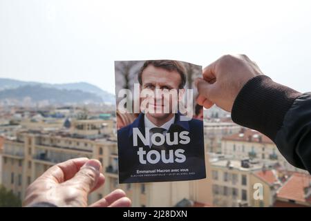 Nice, France. 29th Mar, 2022. A man holds Emmanuel Macron's presidential election 2022 leaflet with a view of properties in Nice. The first round of the French Presidential Election 2022 will take place on Sunday 10th April 2022. (Photo by Dinendra Haria/SOPA Images/Sipa USA) Credit: Sipa USA/Alamy Live News Stock Photo