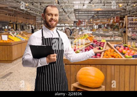 Male shop assistant in a grocery store welcoming customers Stock Photo