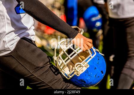 American football player holding protective helmet while waiting Stock Photo