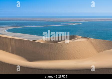 Namibia, the Namib desert, landscape of yellow dunes falling into the sea, the wind blowing on the sand Stock Photo