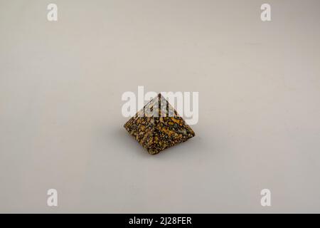 a small pyramid with an orange and black veining against a light background Stock Photo
