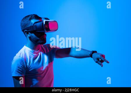 Portrait of man in black t-shirt wearing 3d headset glasses gesturing as if touching something what he doing in virtual reality while playing video Stock Photo