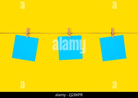 Blue Note papers and decorative pin or clip isolated on yellow background. Office mock up. Top view, flat lay. Colorful office note or sticker papers Stock Photo