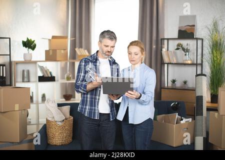An attractive Female at home among things clothes hanging in wardrobe.  Concept Nothing to wear. Redhead Woman decides what to wear. Fashion style.  Shopaholic is upset, sit alone looking up thinking Photos