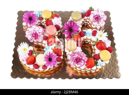 Festive original cake in the form of numbers thirty-six covered with sweets and fruits with flowers. On a white isolated background. Stock Photo