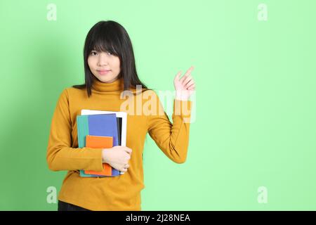 The cute young Asian girl with casual dressed standing on the green background Stock Photo