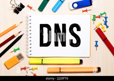 DNS, Domain Name System, text on white card next to notepad and pen on table. Stock Photo