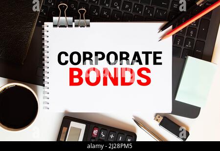 Business reports, blank paper sheet, data tables and charts - directly above view of office table workspace with CORPORATE BONDS text. Stock Photo