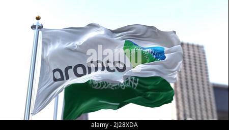 Dhahran, SA, March 2022: The flag of the Aramco oil company waving in the wind with the national flag of Saudi Arabia blurred in the background. Aramc Stock Photo