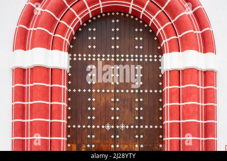 Arched wooden door with decorated white elements. Red style gate frame Stock Photo