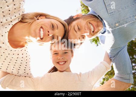 Three heads are better than one. A low angle shot of a happy family in a huddle. Stock Photo