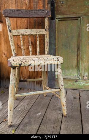 Old distressed wooden chair on back porch of old house. Stock Photo