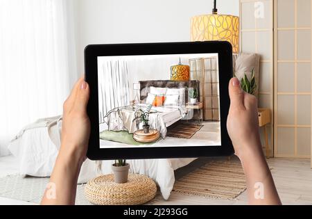 Female designer holding tablet computer with drawing of bedroom interior. New design according to arrangement on sketch Stock Photo