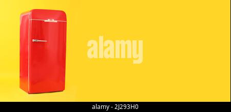Stylish red retro fridge on yellow background with space for text Stock Photo