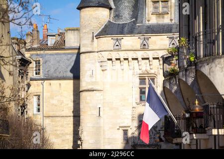 Picture of typical medieval buildings of the city center of Bordeaux, France, with a french flag in front and the porte cailhau in background. Cailhau Stock Photo