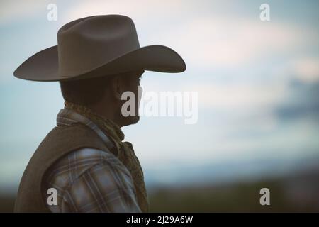 Handsome cowboy with a strong profile, wearing Stetson style hat looks into the distance. Cowboy profile. Marlboro Man. Wyoming cowboy. USA Stock Photo