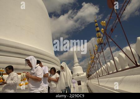 A group of pilgrims praying as they are circling a white, giant stupa at Wat Phra Mahathat Woramahawihan, the main Buddhist stupa in Nakhon Si Thammarat, the largest province in southern Thailand. Stock Photo