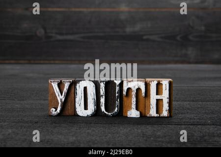 Youth. Word from wooden blocks on a dark textured background. Stock Photo