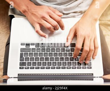 Technology with infinite uses. High angle shot of an unidentifiable man using his laptop at home. Stock Photo