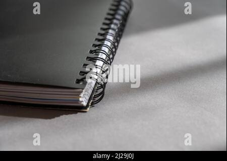Black spring-loaded notebook against a gray background. Close-up of a closed notebook. Stock Photo