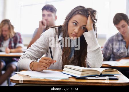 How will I handle this course load. An overworked young student sitting with her head in her hands. Stock Photo