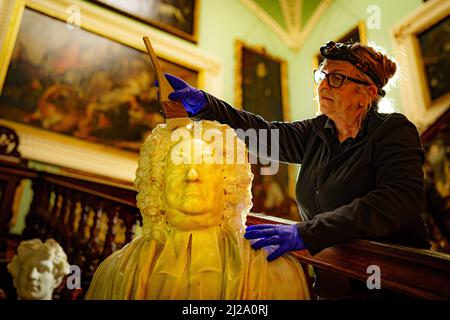 Conservation cleaner Tracie Mason dusts a marble bust of the Reverend George Harbin (c.1665-1774) by John Michael Rysbrack (1694-1770) in the Grand Staircase at Longleat House in Wiltshire ensuring it is ready to start welcoming visitors again on 1st April after a two-year absence. Picture date: Wednesday March 30, 2022. Stock Photo