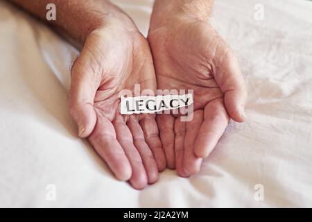 Create a legacy that lasts a lifetime. Cropped shot of a person holding a piece of paper with the word legacy written on it. Stock Photo