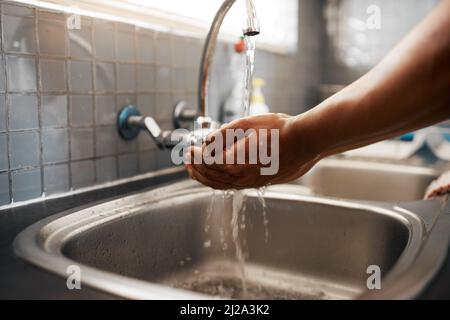 Do you keep your hands clean. Cropped shot of an unrecognizable man washing his hands in the kitchen sink at home. Stock Photo