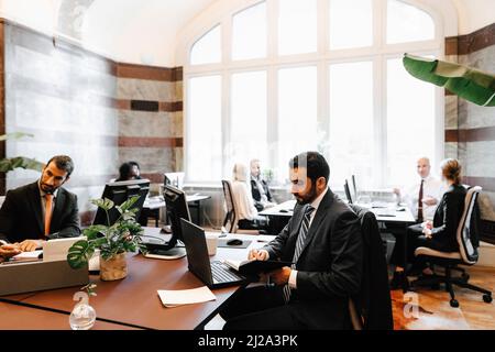 Businessmen sitting at desk working in law office Stock Photo