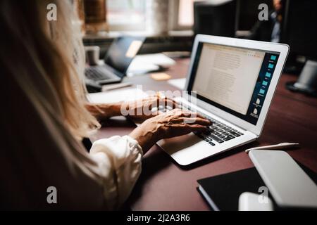 Midsection of female lawyer using laptop while typing at desk in office Stock Photo