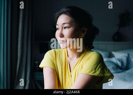 Smiling woman looking away contemplating in bedroom at home Stock Photo