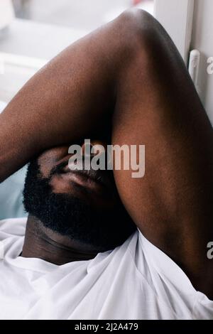 Exhausted man covering eyes while sleeping at home Stock Photo