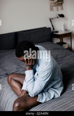 Depressed lonely man sitting on bed at home Stock Photo