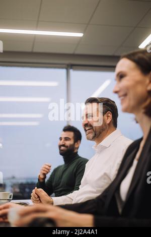 Happy business colleagues working late while discussing in meeting at work place Stock Photo