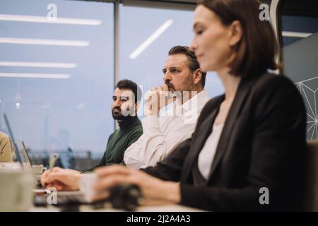 Dedicated businessman with male and female colleagues discussing in meeting at work place Stock Photo