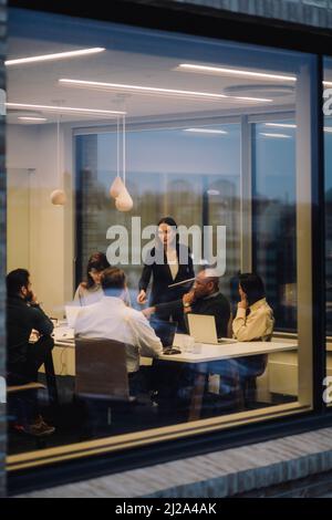 Mature businesswoman discussing with male and female colleagues at work place Stock Photo