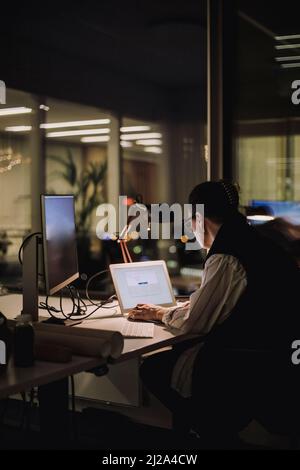 Businesswoman using laptop while working overtime in office at night Stock Photo