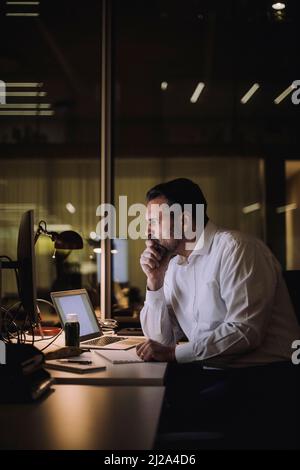 Mature businessman concentrating while working on laptop at work place Stock Photo