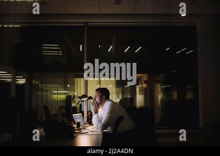 Businessman concentrating while working overtime in office at night Stock Photo