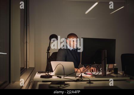 Dedicated businessman using computer while working overtime in office at night Stock Photo