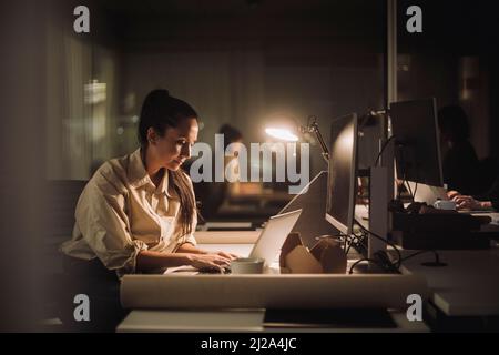 Businesswoman concentrating while working late on laptop in office Stock Photo