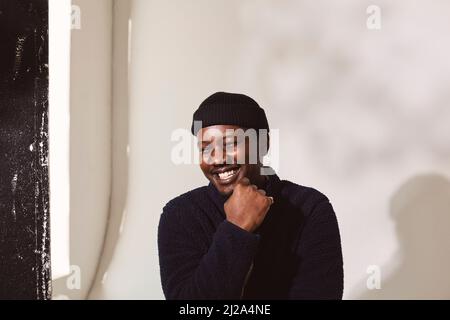 Happy man with hand on chin against white wall Stock Photo
