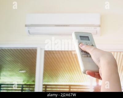 Hand hold remote control directed on the air conditioner Stock Photo
