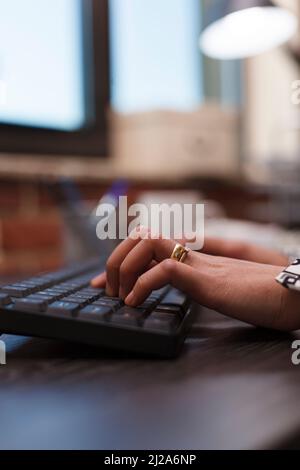 Close up of advertising company businesswoman hands typing on keyboard while working on business project using work computer. Agency office worker on computer developing marketing strategy. Stock Photo