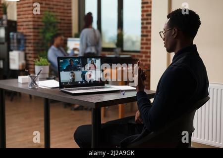 Businessman discussing through videocall with employees about marketing strategy of startup project. Marketing company financial team brainstorming business funding ideas while on digital meeting. Stock Photo
