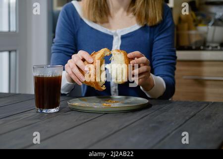 Closeup view of female hands tearing a croissant apart (selective focus photo) Stock Photo