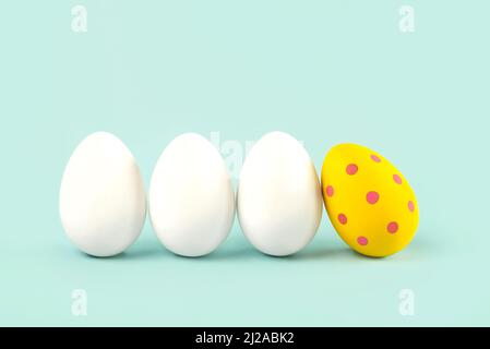 Happy Easter. Close-up of three white eggs and easter painted egg over blue background Stock Photo