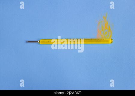 Vintage yellow mercury thermometer with fire painted on top on colorful paper background. Temperature and conceptual photography. Stock Photo