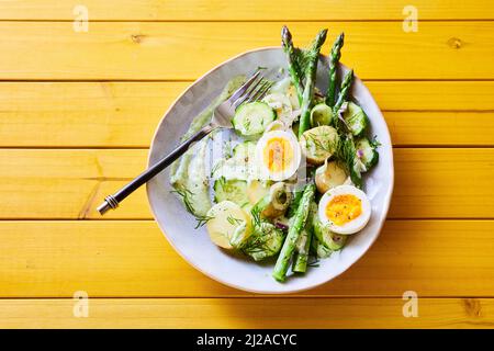 From above of appetizing spring salad with asparagus and eggs and potatoes served for lunch on wooden table Stock Photo